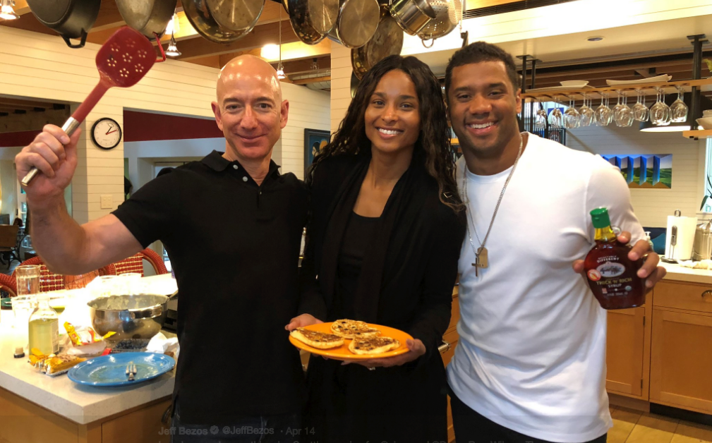 Three smiling people posing in a warm kitchen with pancakes and cooking utensils